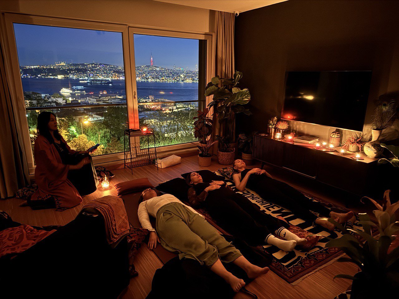 Ays leading a group breathwork session: people lying on mats by candlelight